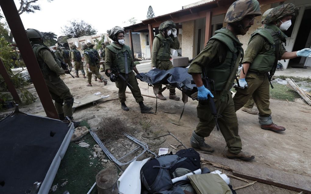 Israëlische militairen dragen een slachtoffer weg uit kibboets Kfar Aza, waar terroristen van Hamas afgelopen zaterdag tientallen inwoners afslachtte. beeld EPA, Atef Safadi