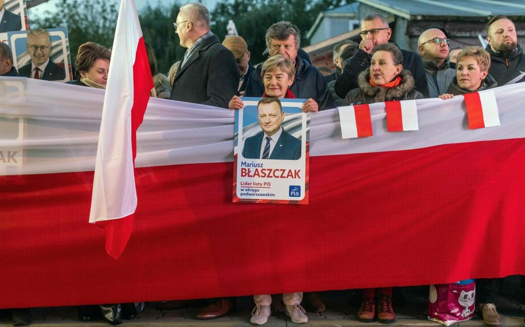 Aanhangers van de regerende partij PiS staan met Poolse vlaggen buiten een tv-studio waar een verkiezingsdebat wordt gehouden. Zondag gaat Polen naar de stembus. beeld AFP, Wojtek Radwanski