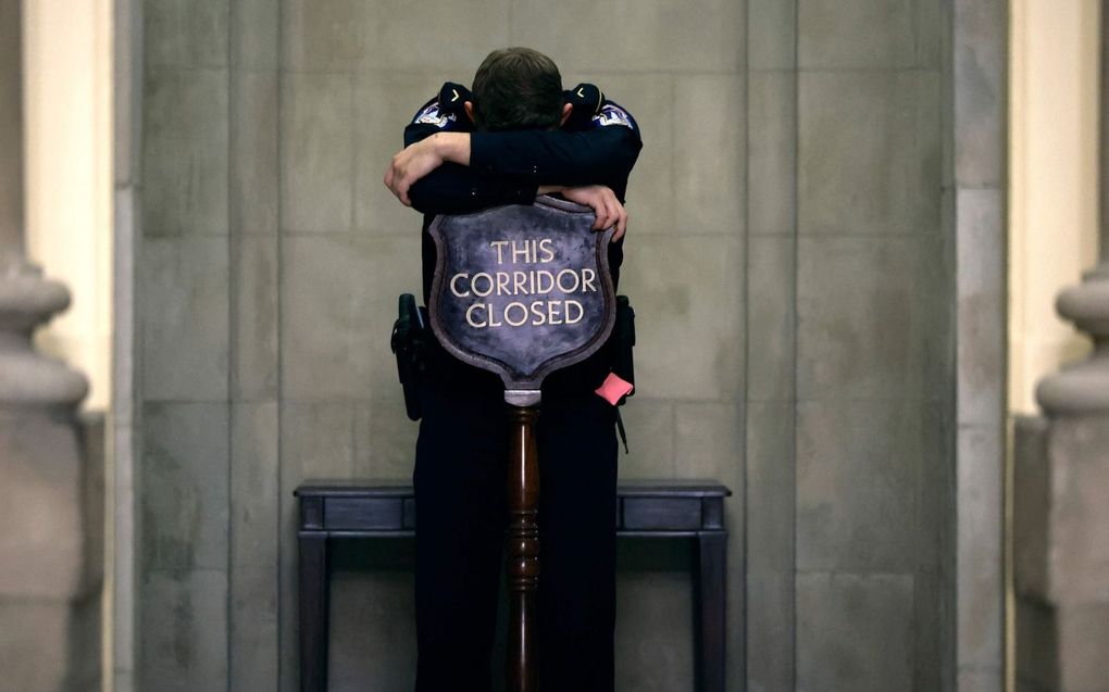 Een lid van de Capitoolpolitie dutte donderdag even in de gang die naar de kantoren van de voorzitter van het Huis van Afgevaardigen leidt. De Republikeinse afgevaardigden spraken urenlang met elkaar over de opvolging van Kevin McCarthy. beeld AFP, Chip Somodevilla