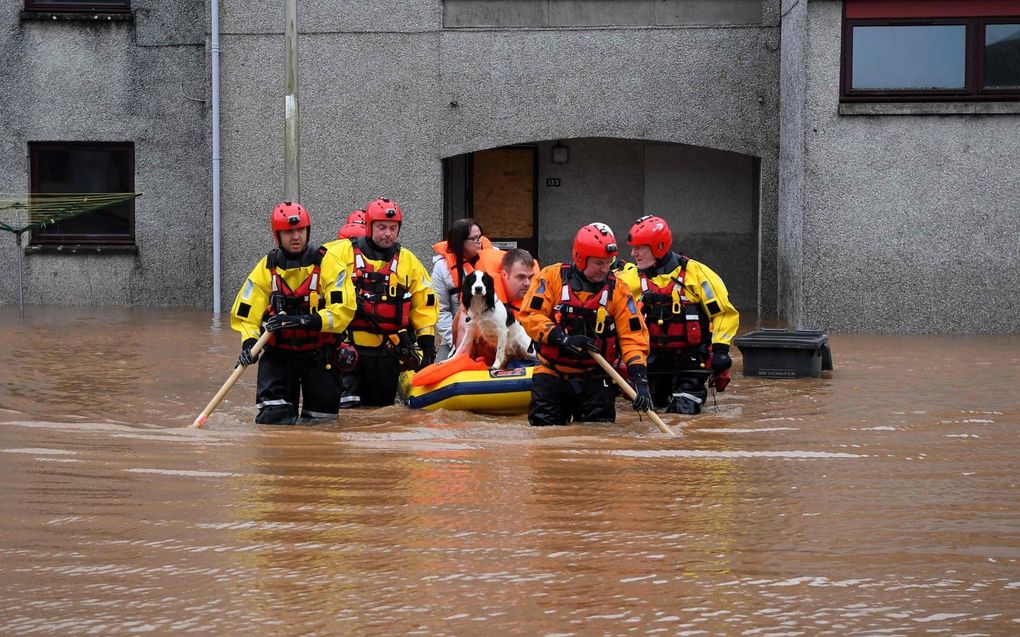 Reddingswerkers brengen een echtpaar en hun hond in veiligheid in Brechin, in het noordoosten van Schotland. beeld AFP, Andy Buchanan