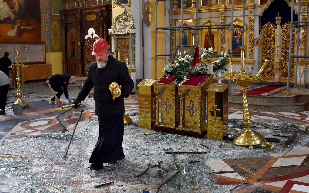 Een orthodoxe priester ruimt op in een kerk in Zaporizje nadat en Russische raket drie mensen doodde. beeld AFP, Andriy Andriyenko