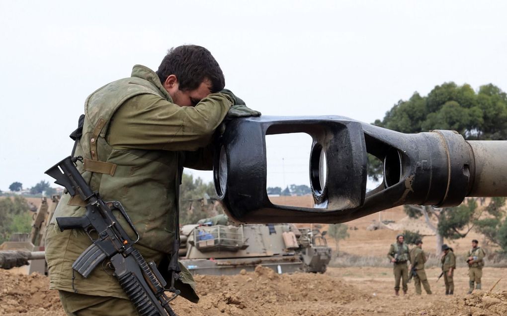 Een vermoeide Israëlische militair rust met zijn hoofd op de loop van een gevechtsvoertuig. beeld AFP, Jack Guez