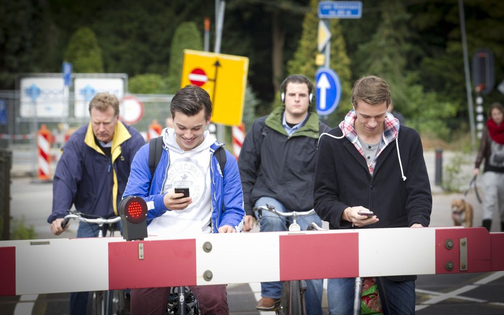 Jongens zijn bezig met hun smartphone voor een spoorwegovergang. beeld ANP, Jeroen Jumelet