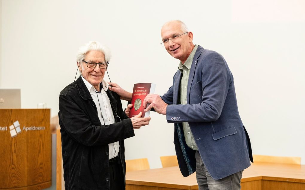 Auteur Ben van den Baar (l.) kreeg woensdag aan de TUA van Pieter de Boer, uitgever bij Royal Jongbloed, het eerste exemplaar van zijn boek uitgereikt: ”De bisschop in de vroege kerk. Verkenning van vijf eeuwen ambtsontwikkeling”. beeld André Dorst