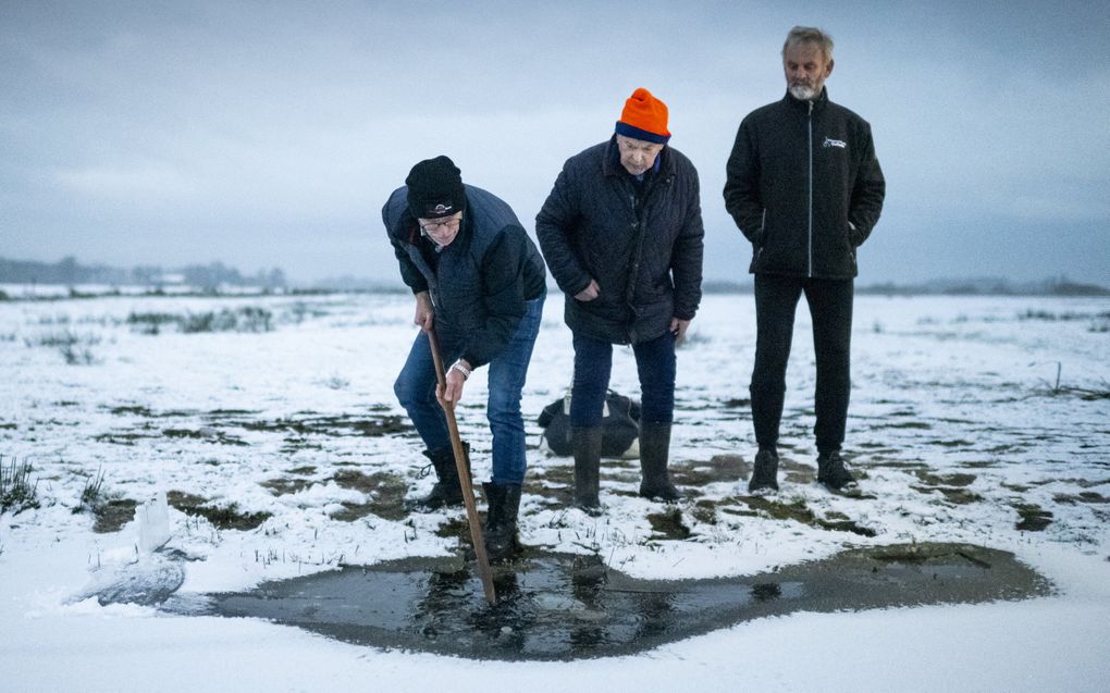 Schaatsers bekijken zaterdag het ijs in de Ryptsjerkerpolder waar nog niet geschaatst kan worden. Vanwege het kleine laagje water is deze plek vaak een van de eerste waar na een nacht vorst geschaatst kan worden. beeld ANP, JILMER POSTMA