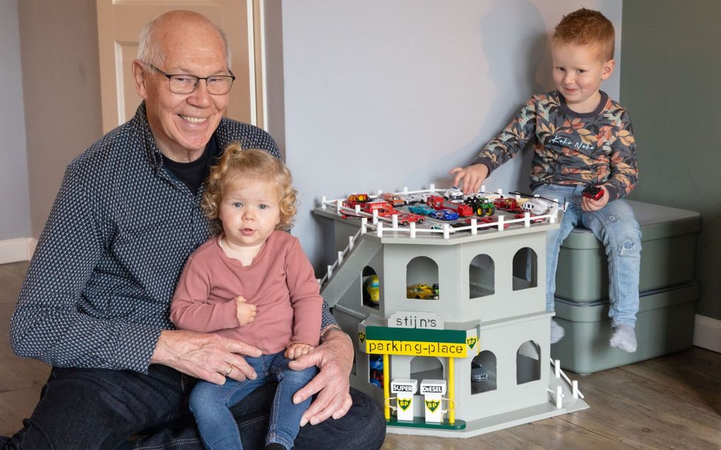 Arie Methorst (74) uit Opheusden met op schoot kleindochter Lotte en kleinzoon Stijn rechts naast hem. Methorst maakte de parkeergarage voor Stijn. „Het volgende project wordt waarschijnlijk een mooi poppenhuis voor Lotte, het zusje van Stijn", vertelt Methorst. beeld RD, Anton Dommerholt