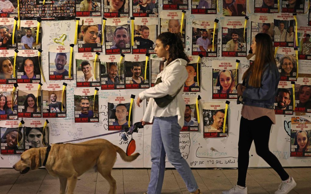 Inwoners van Tel Aviv lopen langs posters van gijzelaars. beeld AFP, Ahmad Gharabli