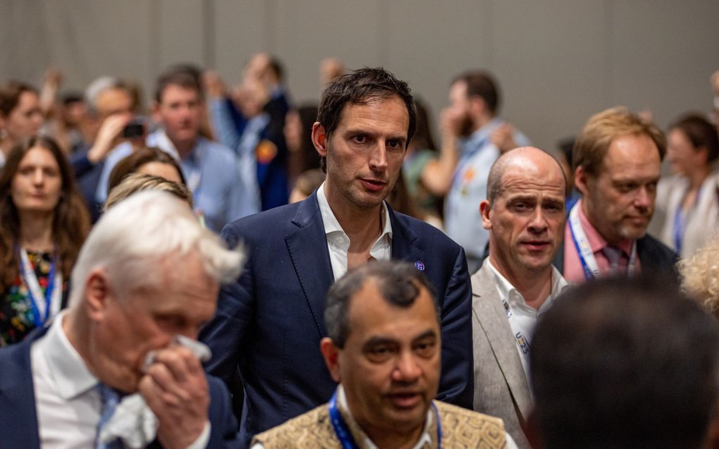 Wopke Hoekstra en Diederik Samson maandag op weg naar onderhandelingen tijdens de klimaattop in Dubai. Op de achtergrond vormen deelnemers uit protest een menselijke ketting door elkaars handen vast te houden. beeld EPA, Martin Divisek