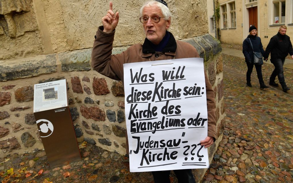 Een man met keppeltje demonstreert naast de Stadskerk van Wittenberg, waar ooit de reformator Maarten Luther preekte. Aan deze kerk hangt al eeuwenlang een ”Jodenzeug”, een beeld van Joden in obsceen contact met een vrouwelijk varken. beeld AFP, John Macdougall