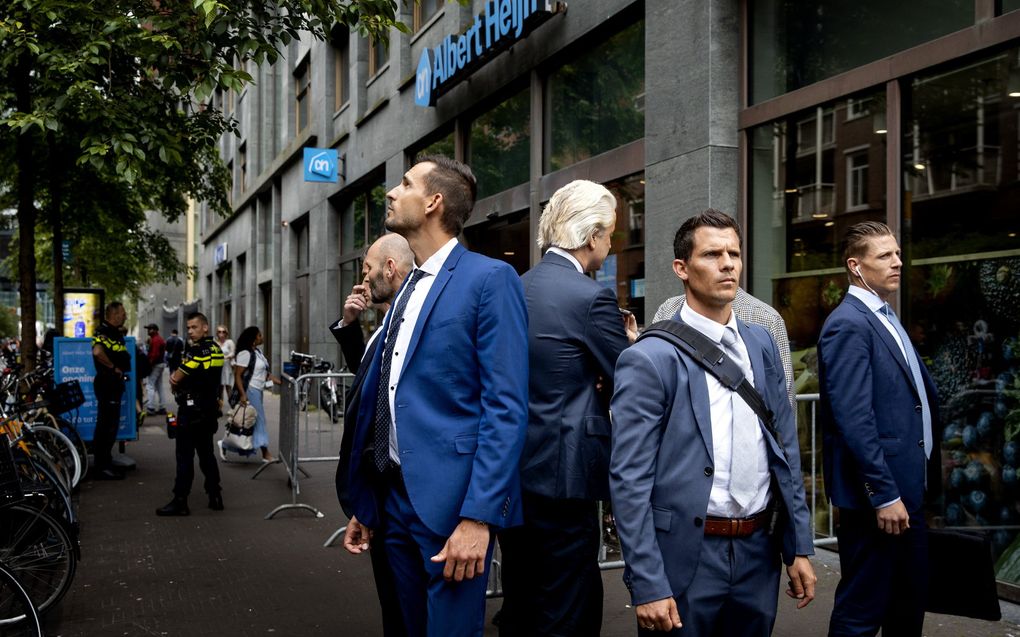 Geert Wilders (PVV), omringd door tal van beveiligers, legt een bos bloemen op de Turfmarkt in Den Haag voor een doodgestoken Albert Heijn-medewerkster. beeld ANP, Koen van Weel