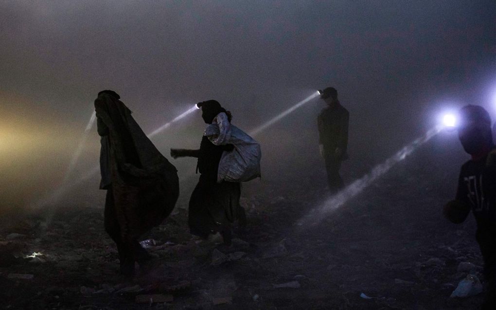 Mensen zoeken naar herbruikbare materialen op een vuilnisbelt in de stad Basra, in Zuid-Irak. beeld AFP, Hussein Faleh