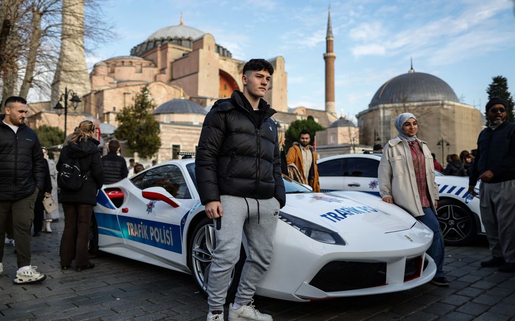 Turken poseren met een politieauto voor de Hagia Sophia in Istanbul. De Turkse politie nam 23 luxe auto’s in beslag van criminele organisaties en gebruikt ze nu zelf. Beeld EPA, ERDEM SAHIN