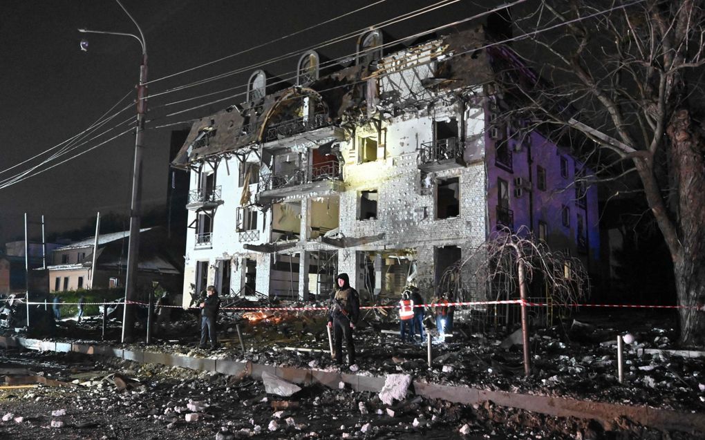 Reddingswerkers zetten een zwaarbeschadigd hotel in Charkiv af. Het gebouw werd donderdag getroffen door Russische raketten.  beeld AFP, Sergey Bobok