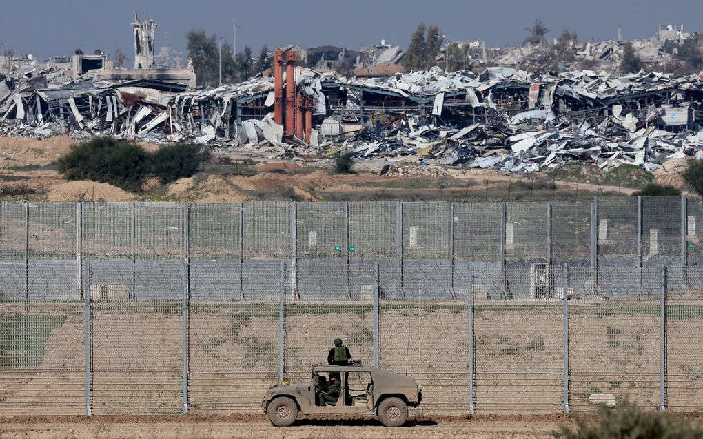 Op een foto, genomen op 19 januari 2024 vanaf een positie in het zuiden van Israël langs de grens met de Gazastrook, is te zien hoe een Israëlisch legervoertuig langs het hek in Israël rijdt te midden van aanhoudende gevechten tussen Israël en de terreurbeweging Hamas.
 beeld AFP, JACK GUEZ