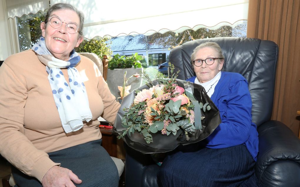 Maatje van Maurik-van de Woestijne (r.) krijgt bloemen van haar zus Riet van de Woestijne. „Het maakt niet uit wanneer en waarvoor Van de Woestijne belt, haar zus komt altijd aansnellen.” beeld VidiPhoto