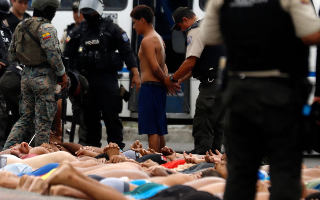 Criminelen wachten, met de handen op de rug gebonden, op transport naar de gevangenis. Sinds in Ecuador de noodtoestand van kracht is, zijn al duizenden jonge mannen opgepakt. beeld AFP