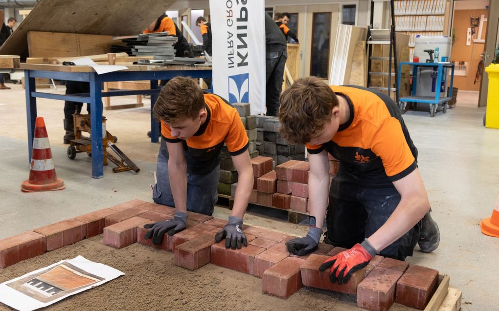 Twee scholieren leggen bakstenen in een gespreid bedje van zand. beeld RD, Anton Dommerholt