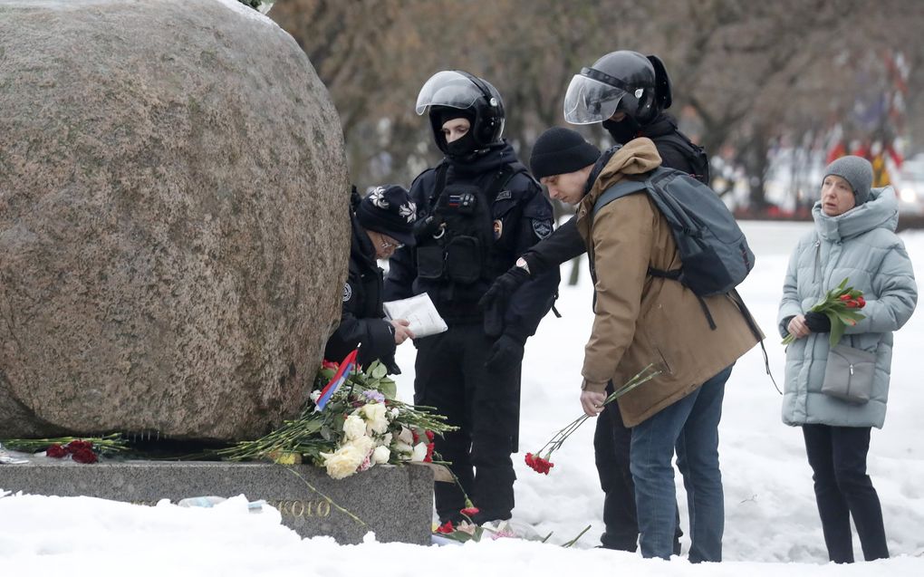 Onder toeziend oog van de politie leggen mensen bloemen ter nagedachtenis aan Navalni in Sint Petersburg. beeld EPA, ANATOLY MALTSEV