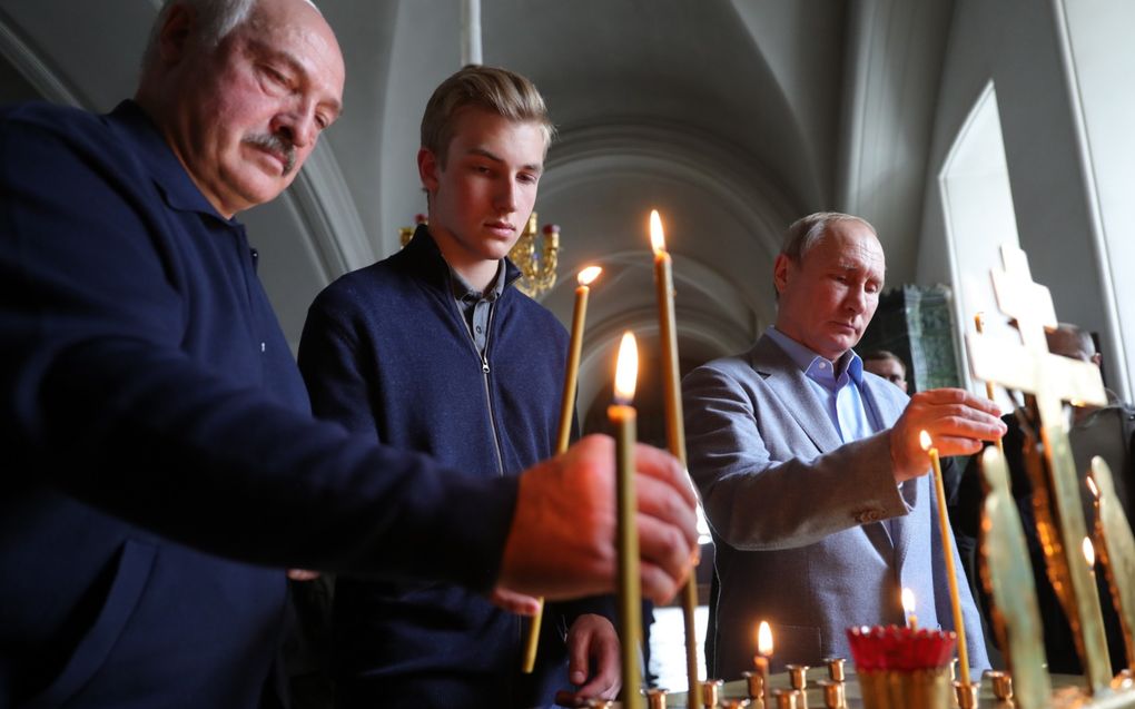 De Wit-Russische president Lukashenko (links) met zijn Nikolai (midden) en de Russische president Poetin (rechts) in een Russische kathedraal. beeld EPA, Michael Klimentyev