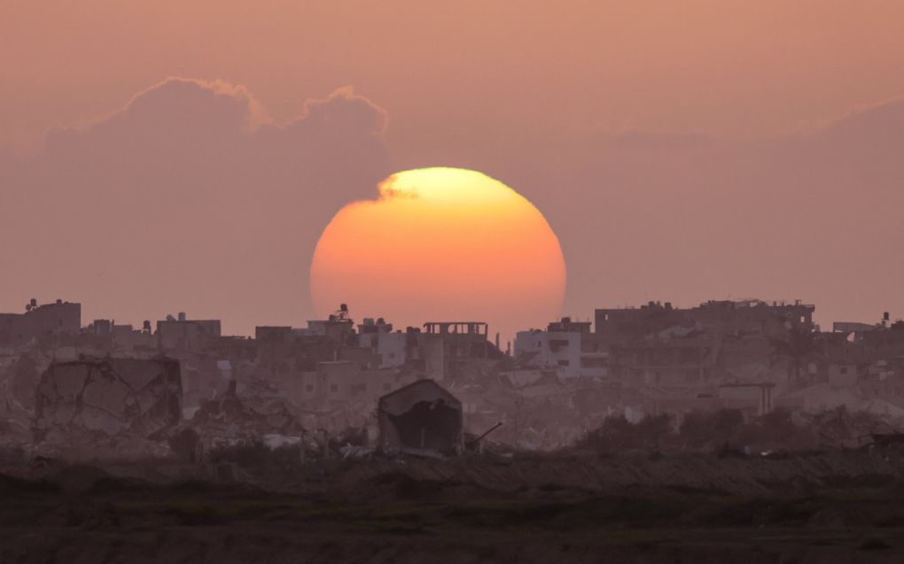 Zonsondergang achter verwoeste gebouwen in Gaza, te midden van voortdurende gevechten tussen Israël en Hamas. beeld AFP, Menahem Kahana