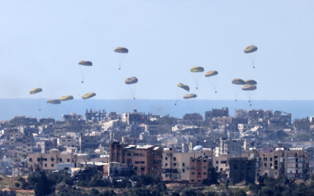 Hulpgoederen worden gedropt boven de Gazastrook door militaire vliegtuigen. Beeld AFP, Menahem Kahana