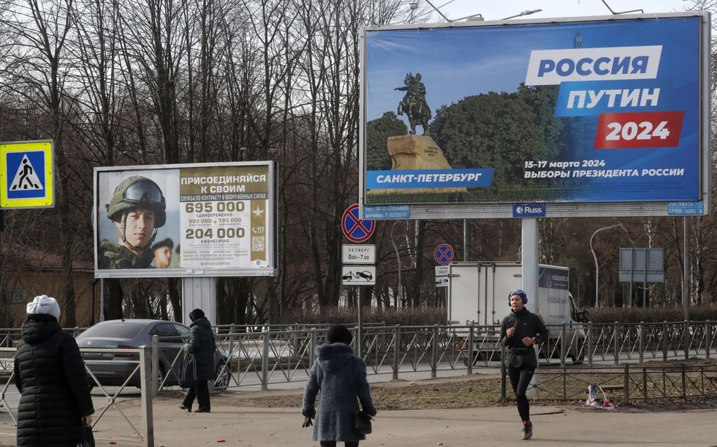 Een campagneposter voor de Russische president en presidentskandidaat Vladimir Poetin (R) naast een wervingsbord voor het leger, in Sint-Petersburg. beeld EPA, Anatolij Maltsev