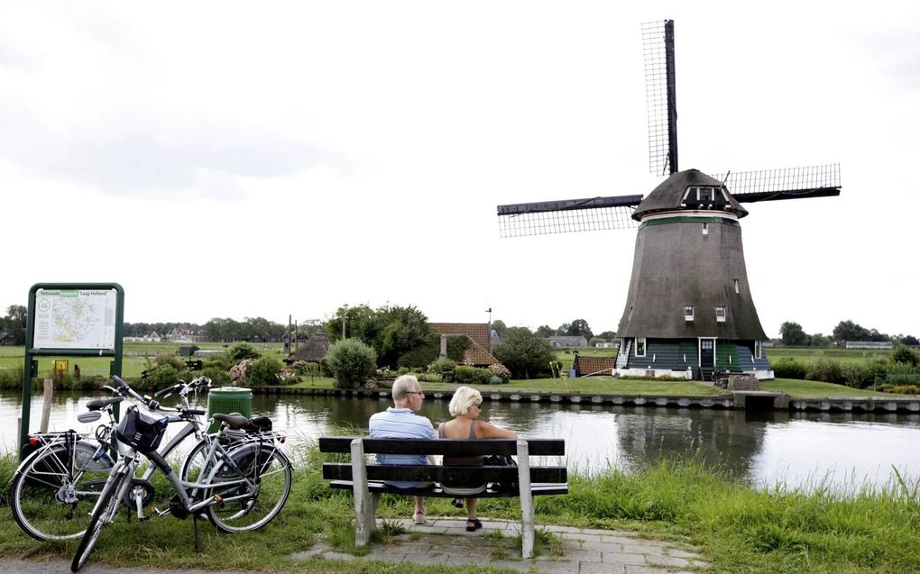 Fietsers rusten langs de Ringvaart van De Beemster. Fietsen en molens worden door veel Nederlanders gezien als typerend voor de Nederlandse identiteit. beeld ANP, Koen Suyk