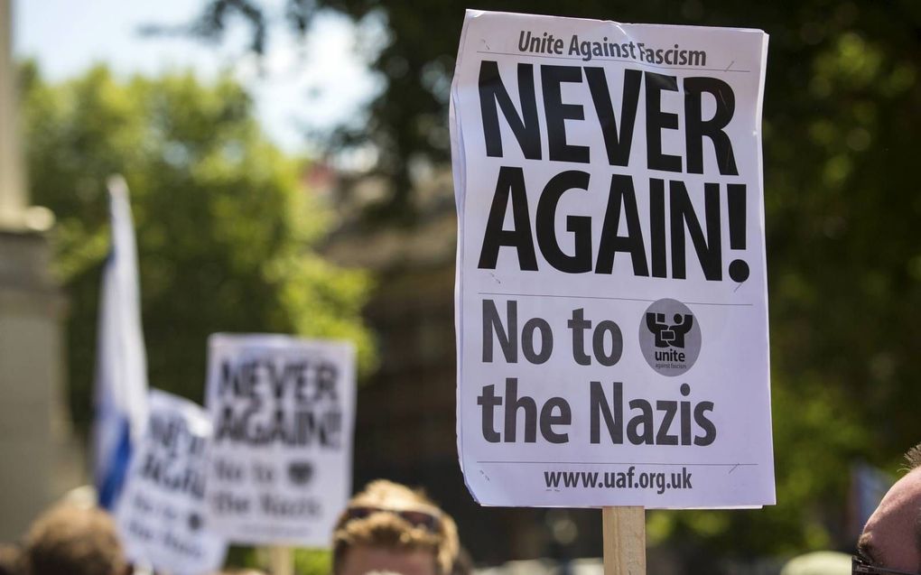 ”Nooit weer" staat te lezen op een bord dat een betoger omhoog houdt tijdens een  demonstratie in Londen op 4 juli waar antisemitistische slogans werden geroepen. beeld AFP, Jack Taylor