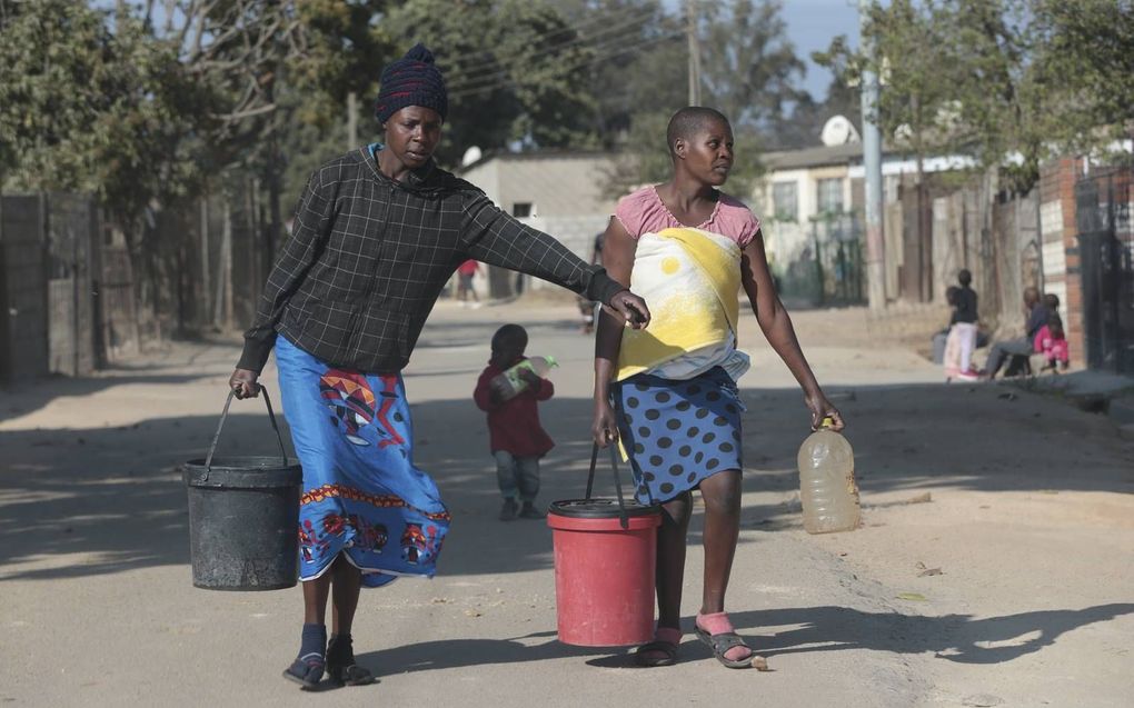 Vrouwen dragen emmers met water in Mabvuku, een plaats nabij de Zimbabwaanse hoofdstad Harare. Door een langdurige droogteperiode zijn veel bronnen opgedroogd en moeten mensen eindes lopen om aan water te komen. beeld EPA, Aaron Ufumeli