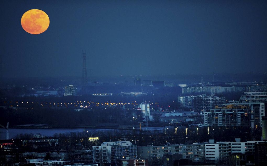 De mens is geschapen voor de aarde, maar betekent dat automatisch dat hij zich niet met de maan mag bemoeien? Foto: volle maan boven Rotterdam. beeld ANP, Robin Utrecht