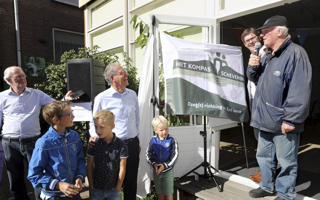 Vaste bezoeker Theo Secrève (uiterst rechts) mocht zaterdag het nieuwe logo onthullen van inloophuis Het Kompas, dat is verhuisd van de Apeldoornselaan in Den Haag naar de Keizerstraat in Scheveningen. beeld Dick Teske