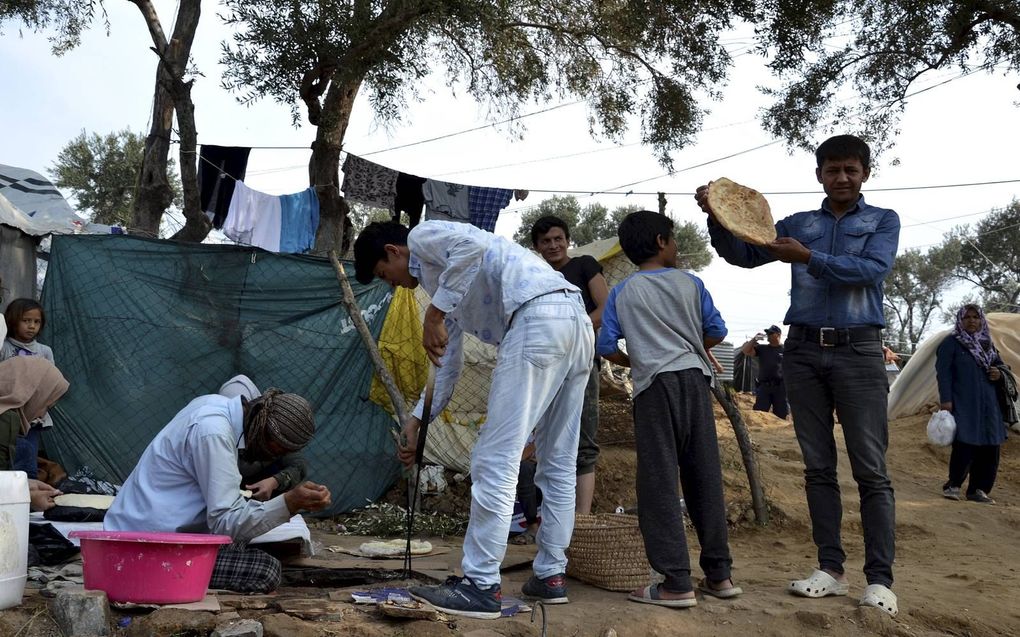 Vluchtelingen hebben een tent opgeslagen buiten het officiële kamp Moria, dat overvol is. Sommigen bakken zelf brood. beeld EPA, Stratis Balaskas
