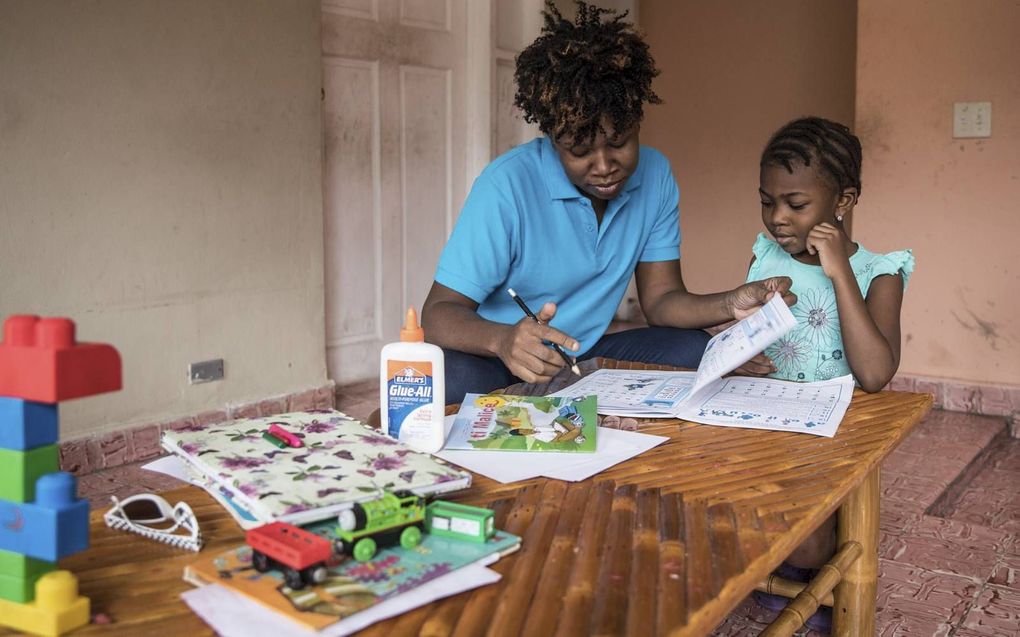 De vijfjarige Lyne-Renée krijgt thuisonderwijs van haar moeder. Veel scholen in Haïti zijn al weken dicht door de politieke crisis. beeld AFP, Valérie Baeriswyl