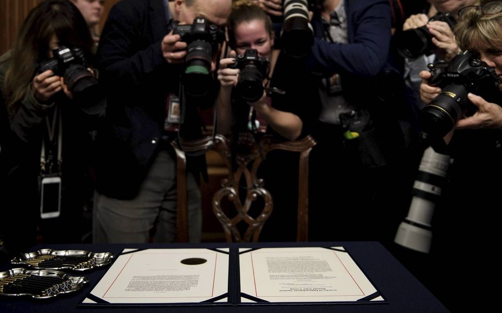 Fotografen verdringen zich rond de papieren waarop de officiële aanklachten tegen president Donald Trump zijn geformuleerd. beeld AFP, Bredan Smialowski