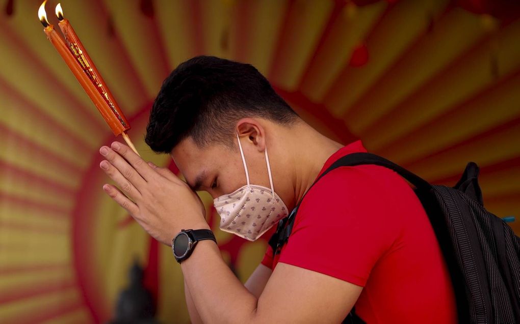 Een man draagt een beschermend masker terwijl hij bidt in een Chinese tempel in Bangkok, de hoofdstad van Thailand. Thaise gezondheidsfunctionarissen zijn extra alert nadat duidelijk werd dat er in Thailand veertien mensen besmet zijn met het coronavirus.