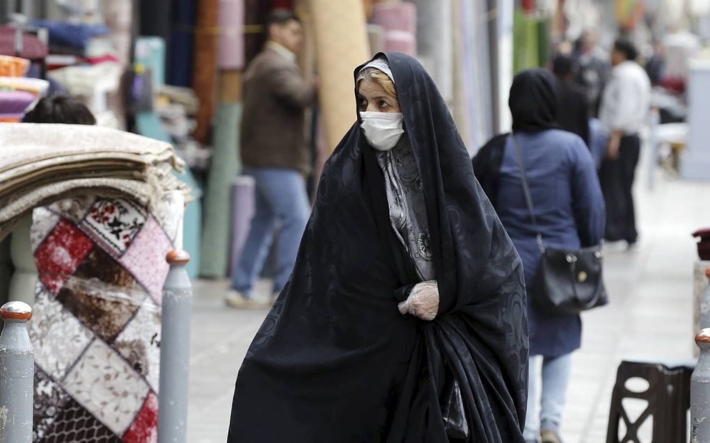 Een Iraanse vrouw draagt een gezichtsmasker en beschermende handschoenen tijdens het winkelen op de grote bazaar in Teheran. beeld EPA, Abedin Taherkenareh