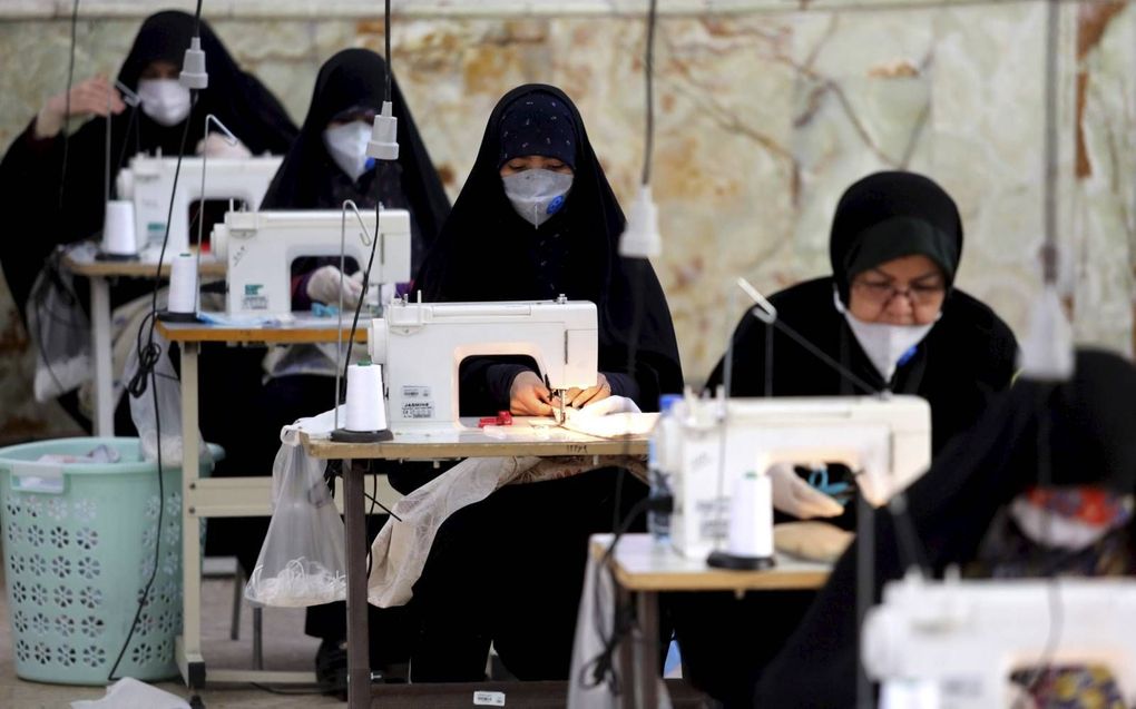 Iraanse vrouwen, leden van de paramilitaire organisatie Basij, maken gezichtsmaskers en andere beschermende items in een moskee in de Iraanse hoofdstad Teheran. beeld AFP, Atta Kenare