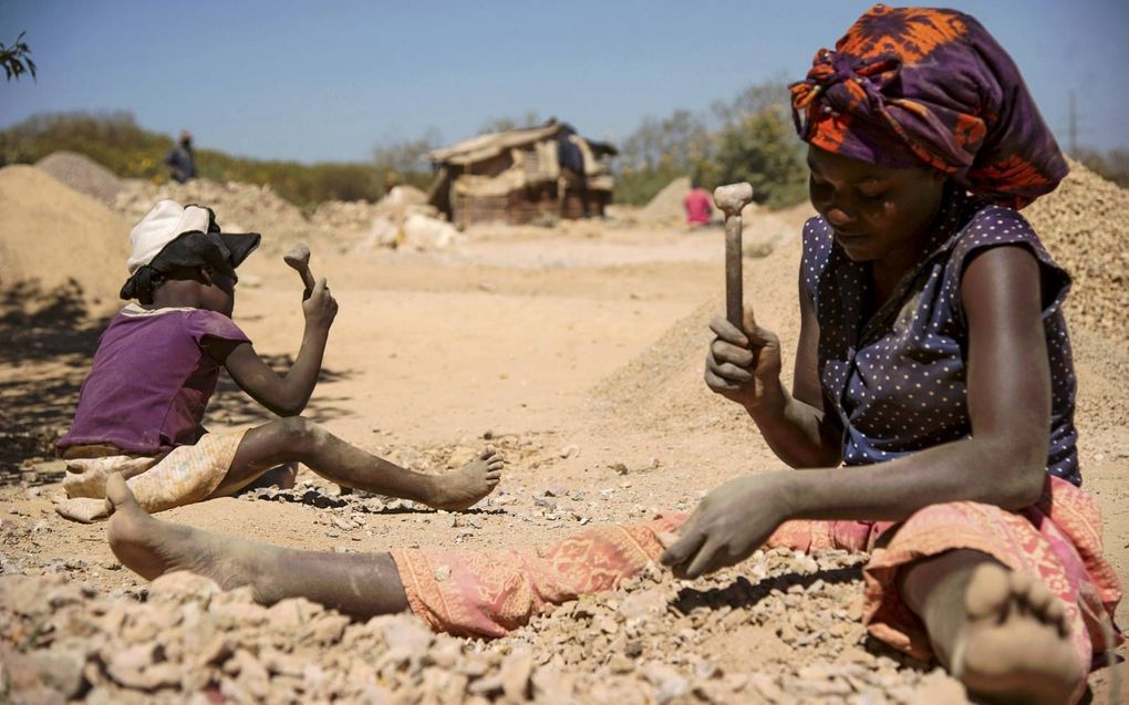 Foto: Congolese vrouw breekt met haar kind stenen uit een kobaltmijn. beeld AFP, Junior Kannah