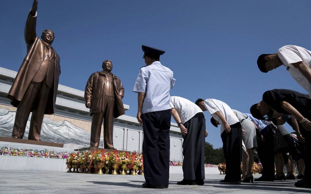 Mensen betuigen hun respect voor bronzen beelden van wijlen leiders Kim Il Sung (l.) en Kim Jong Il. Noord-Koreaanse leiders worden als goden vereerd. Het christendom is verboden in het land. beeld AFP, Andrew Harnik