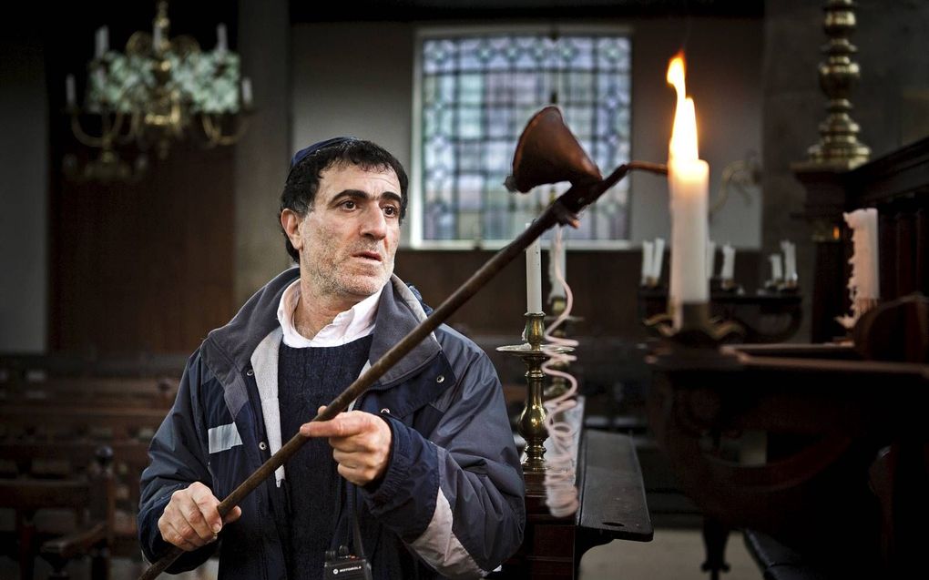 Een man steekt kaarsen aan in de Portugese Synagoge in Amsterdam. Onder andere de gezamenlijke gebeden en het lezen uit de Thorarol kunnen niet plaatsvinden. beeld ANP, Ilvy Njiokiktjien