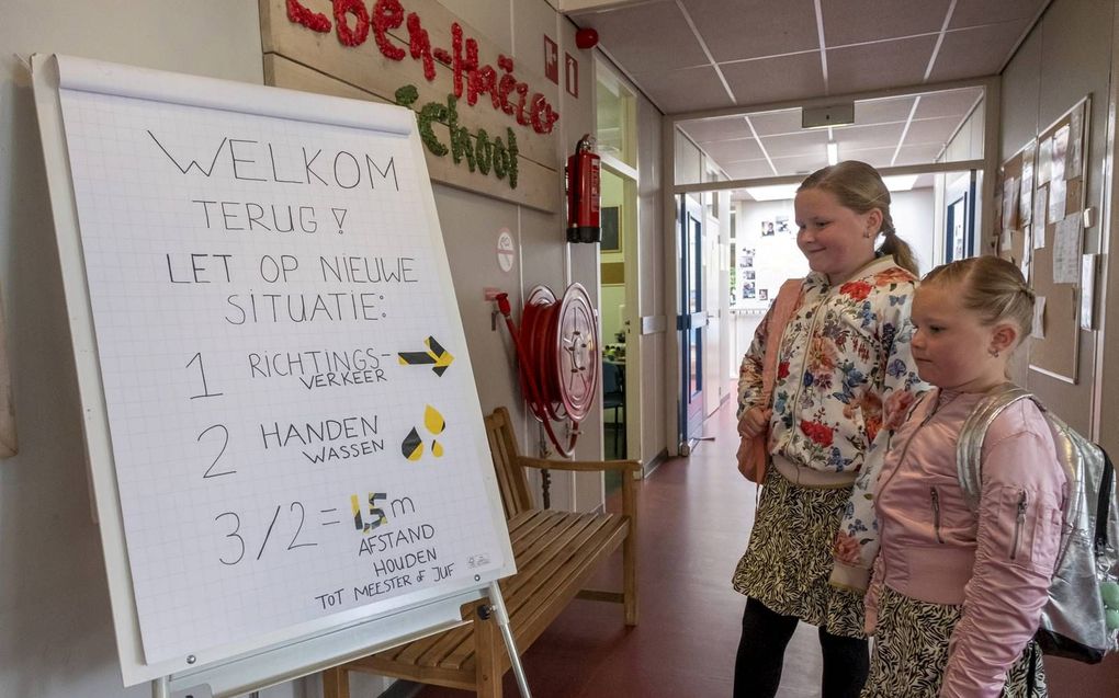 Noa en Selena de Visser bekijken een instructiebord in de hal van de Eben-Haëzerschool in Oostkapelle. beeld Dirk-Jan Gjeltema