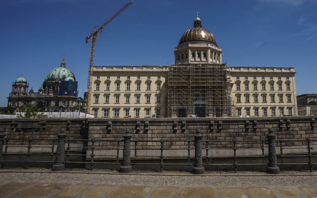 Het stadspaleis in Berlijn, met links de Berlijnse dom. Op het paleis-in-herbouw werd vorige week het nieuwe gouden kruis aangebracht. Samen met de Bijbels inscriptie onderaan de koepel veroorzaakt dit de nodige discussie onder politici én kerken in Berli