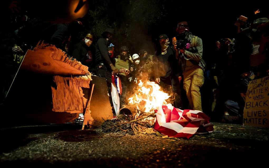 Demonstranten verbranden een Amerikaanse vlag tijdens een protest tegen racisme en politiegeweld in het centrum van de Amerikaanse stad Portland in de staat Oregon. beeld EPA, Etienne Laurent