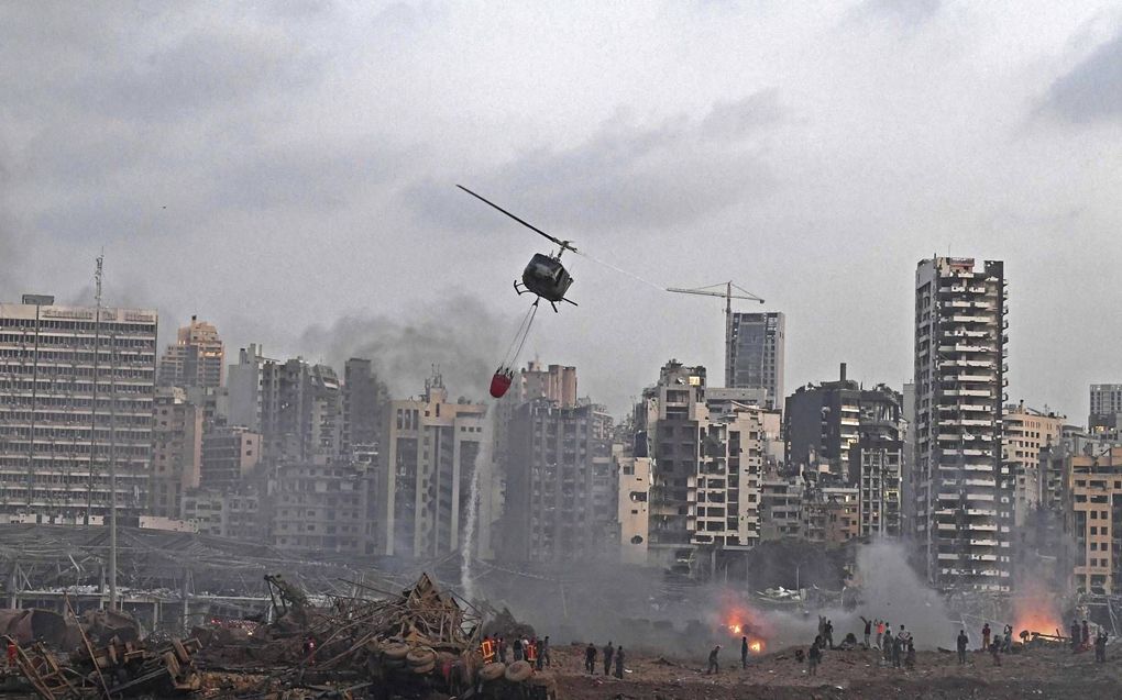 Een helikopter probeert meerdere branden te blussen op de plaats van de enorme explosie die dinsdag het hart van de Libanese hoofdstad trof. beeld AFP