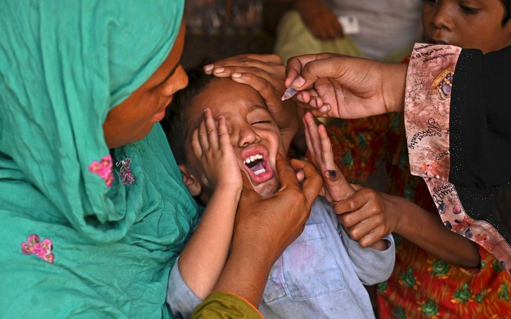 Een gezondheidswerker dient het poliovaccin toe aan een kind in de Pakistaanse stad Lahore, vorige week. Pakistan en Afghanistan zijn de laatste landen waar het virus nu nog rondwaart. beeld AFP, Arif Ali