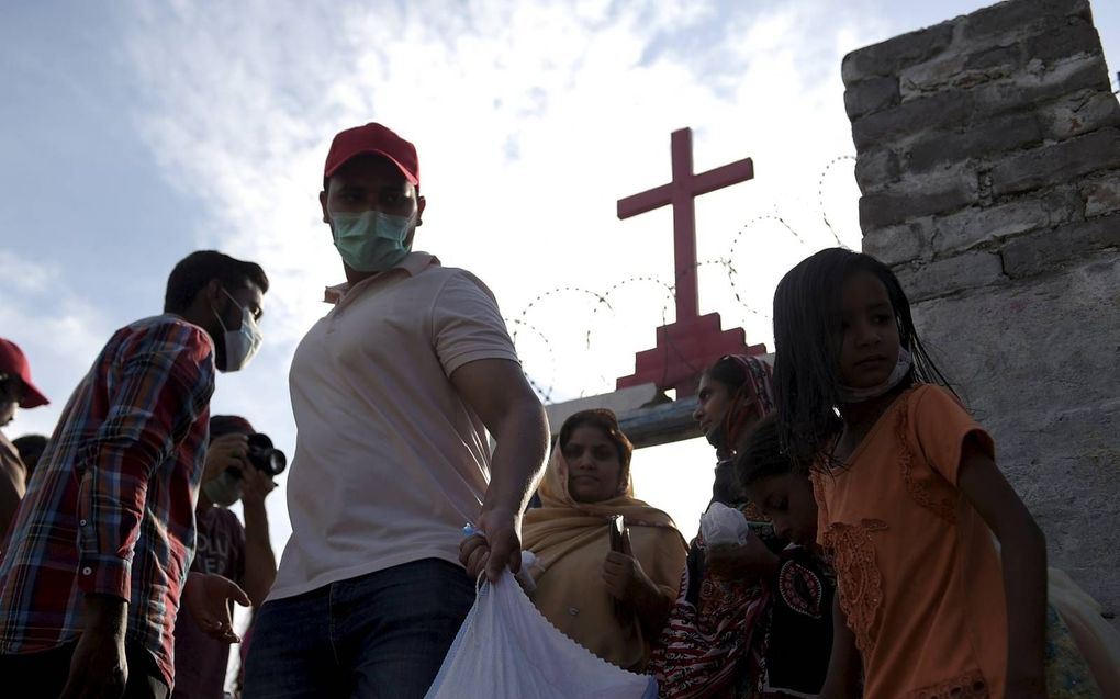 Een man voorziet Pakistaanse christenen buiten een kerk van voedsel. Door de coronacrisis is deze minderheidsgroep nog kwetsbaarder. beeld AFP, Farooq Naeem.