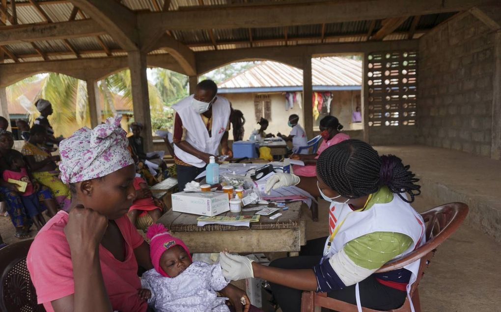 Een gezondheidswerker van Artsen zonder Grenzen verleent hulp aan moeder en kind in een noodhospitaal in Sierra Leone. Artsen vrezen dat meer kinderen zullen overlijden aan bijvoorbeeld malaria nu veel ouders vanwege het coronavirus ziekenhuizen vermijden