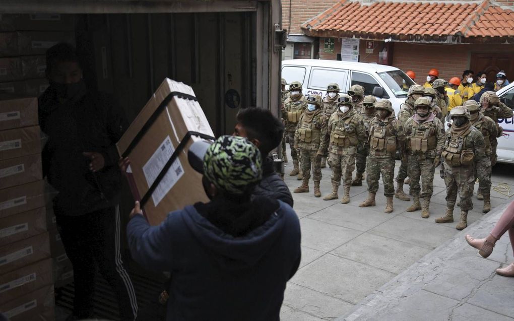 Onder het toeziend oog van de militaire politie laden medewerkers van het Boliviaanse kiesgerechtshof een vrachtwagen met verkiezingsmateriaal uit in La Paz, de administratieve hoofdstad van Bolivia. Het Zuid-Amerikaanse land kiest zondag een nieuwe presi