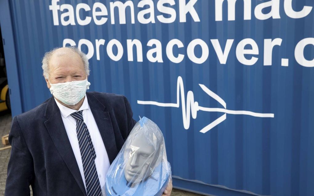 Jan van Tienhoven poseert met twee van zijn uitvindingen: het mondkapje in de speciale houder en de volgelaatsmasker. beeld RD, Anton Dommerholt