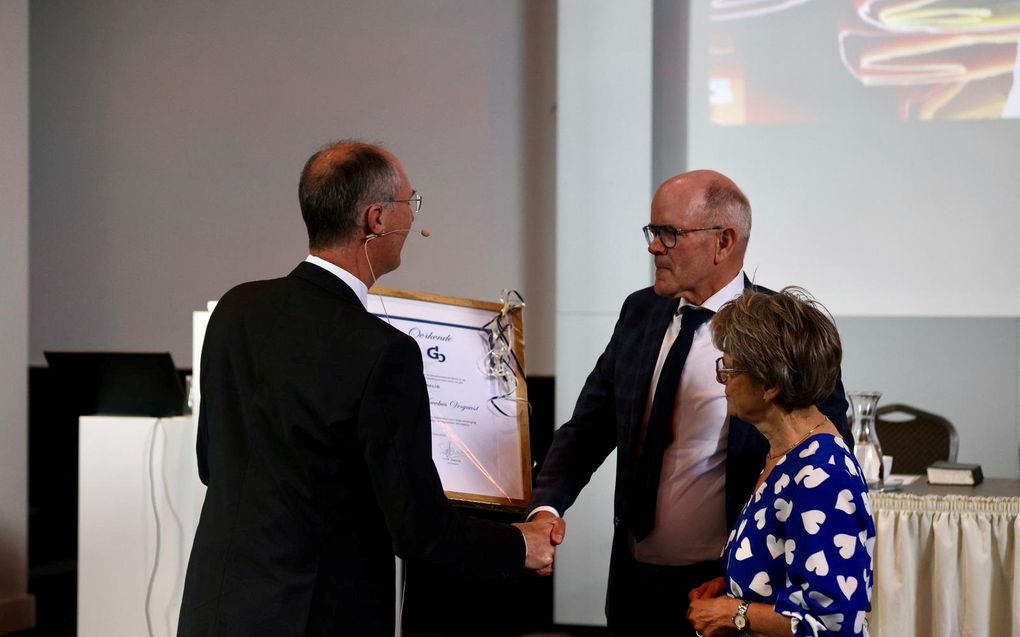 Piet Vergunst (m.) is donderdag in Putten benoemd tot erelid van de Gereformeerde Bond. Hij krijgt uit handen van ds. J.A.W. Verhoeven (l.) een oorkonde. beeld André Dorst